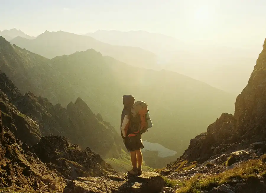 A hiker overlooking a mountain valley at golden hour.