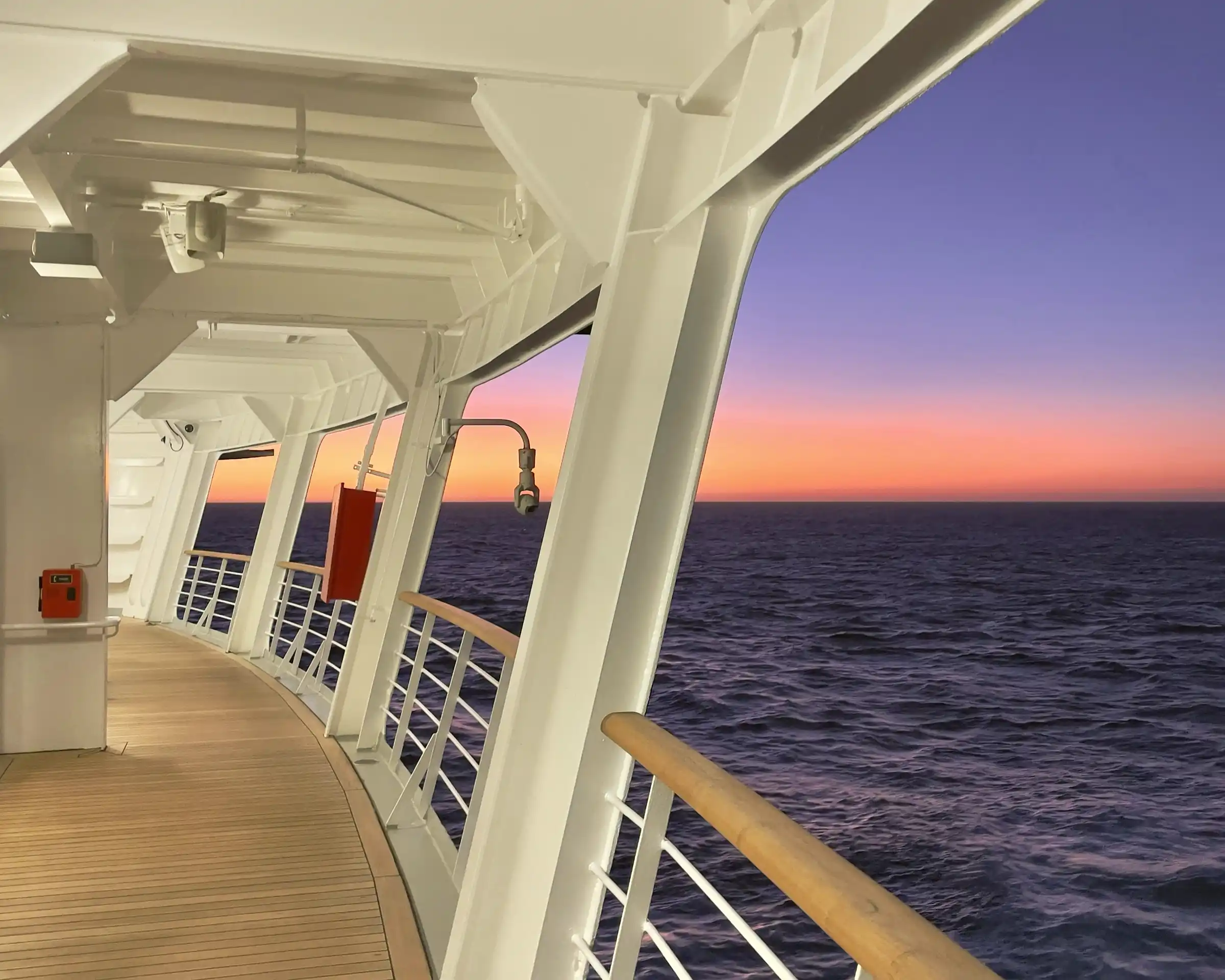 A ship deck rail at dusk, open water.