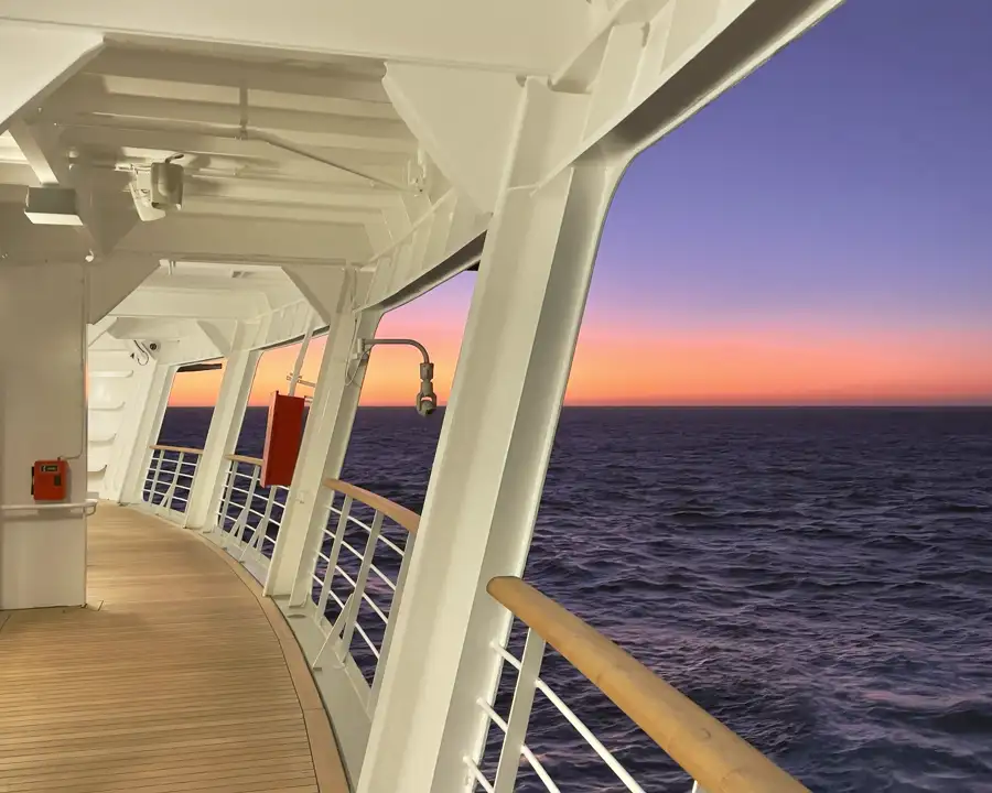 A ship deck rail at dusk, open water.