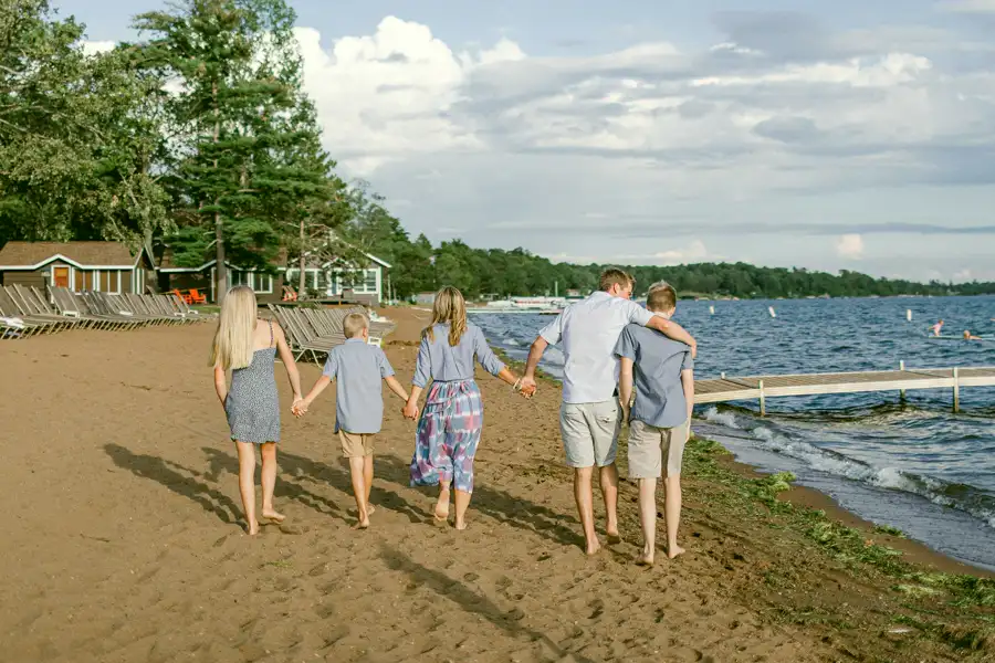 A family walking a beach at sunset, seen from behind.